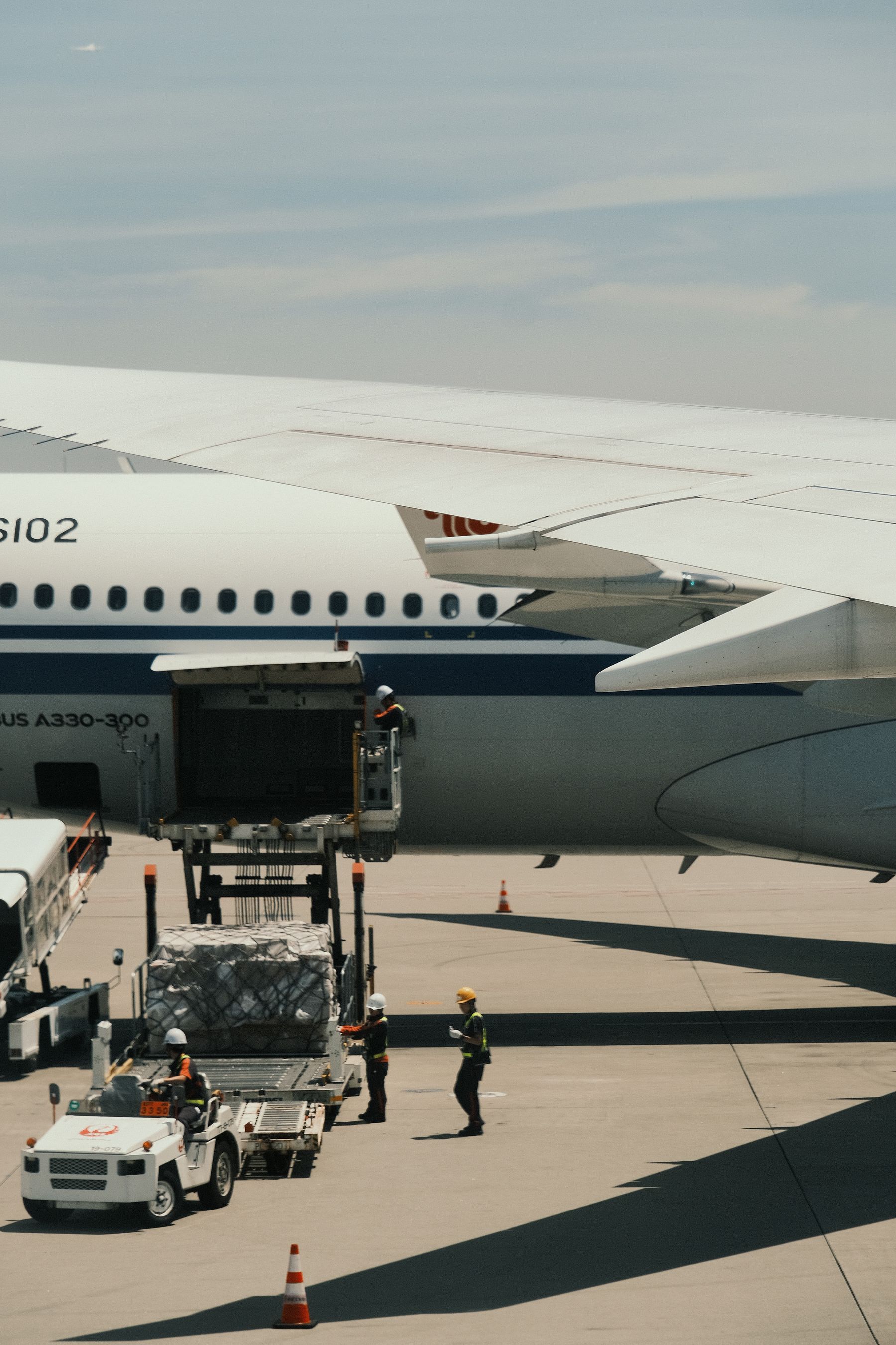 Ground crew loading cargo into an aircraft with a high-loader